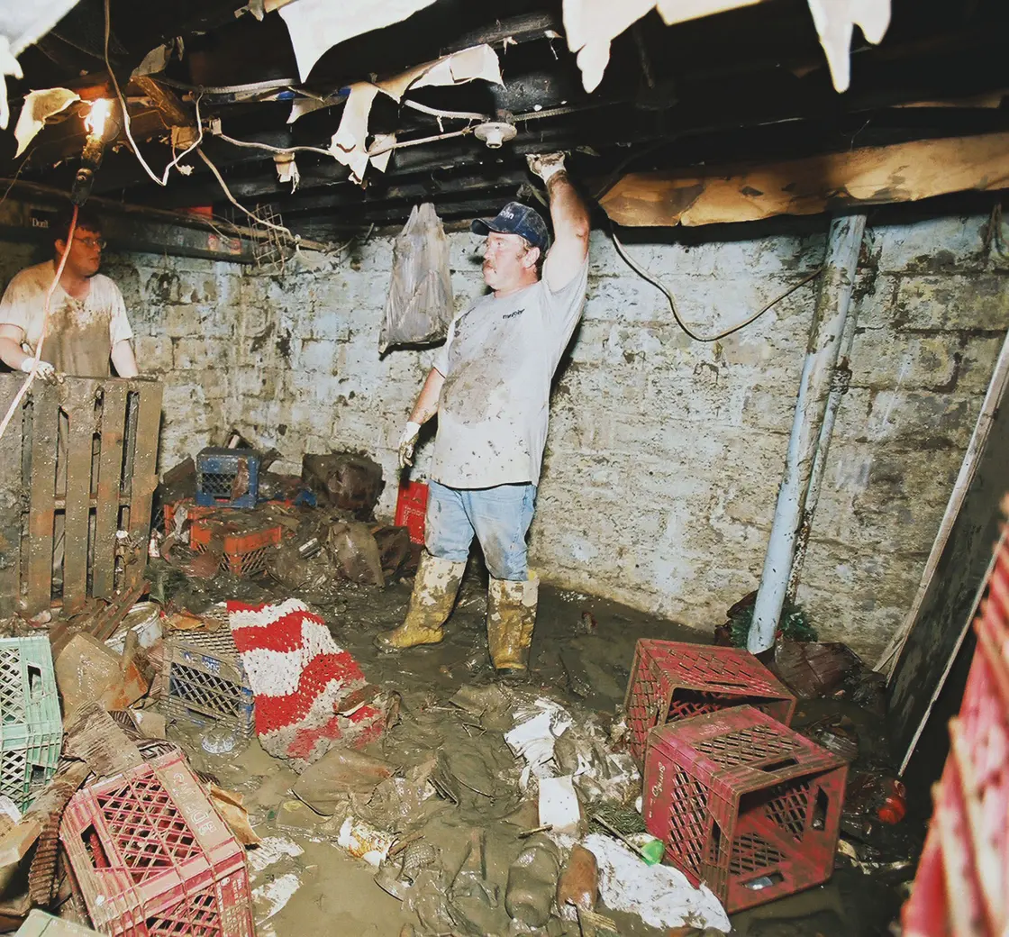 Flood-damaged basement with wet stone walls and debris on the floor