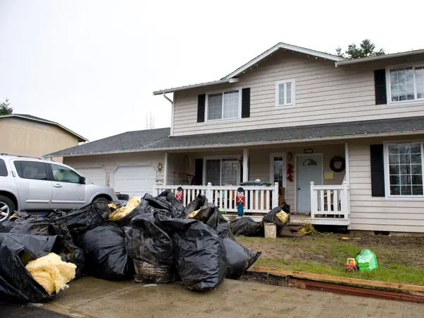 Bags of water-damaged belongings piled in front of a house after a flood